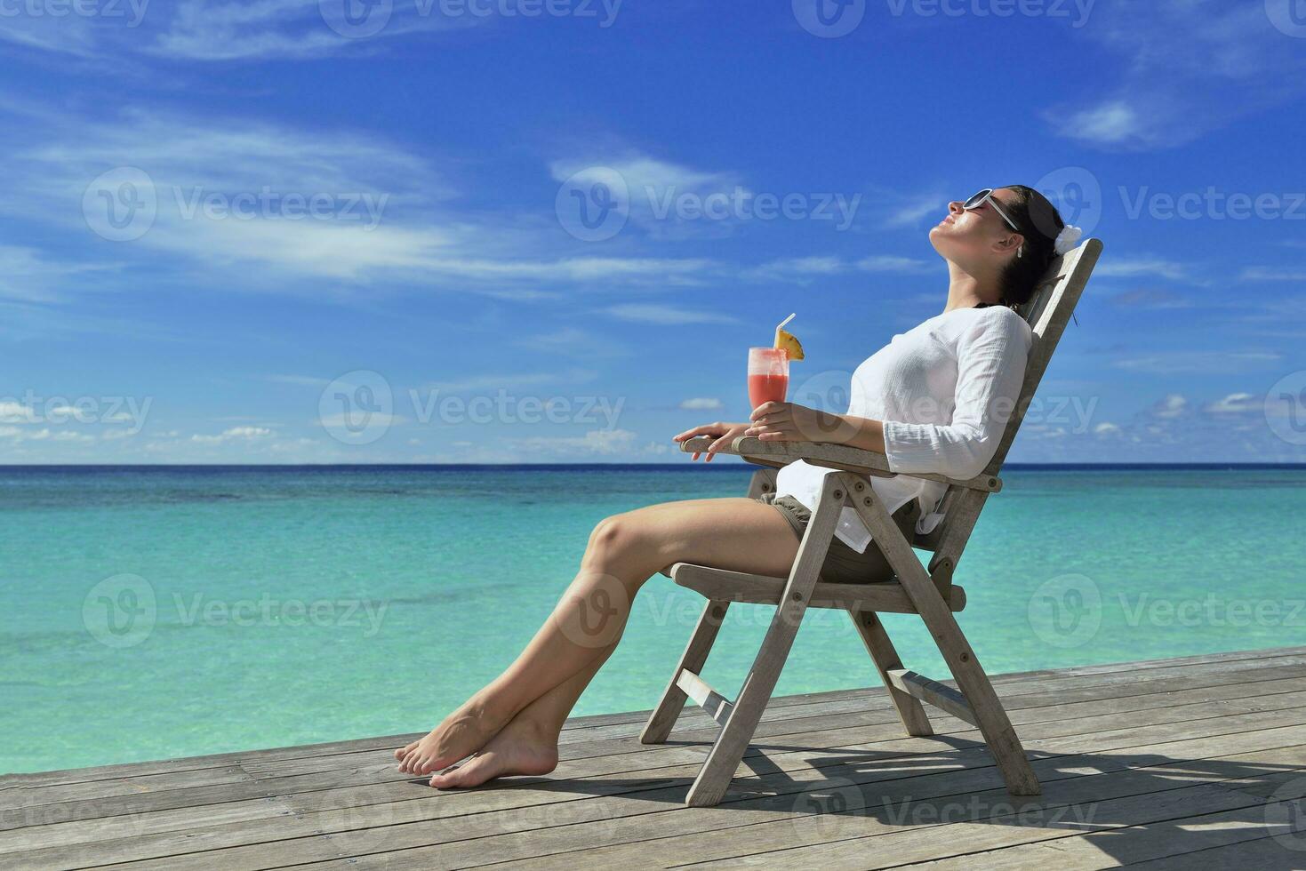 Beautiful young woman with a drink by the sea photo