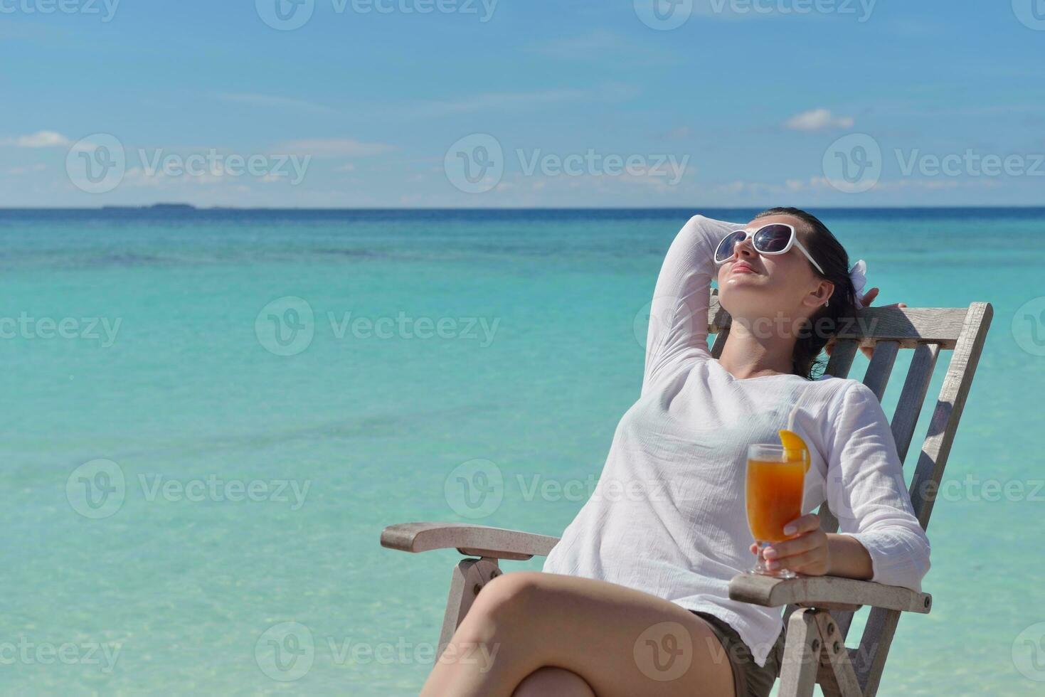 Beautiful young woman with a drink by the sea photo