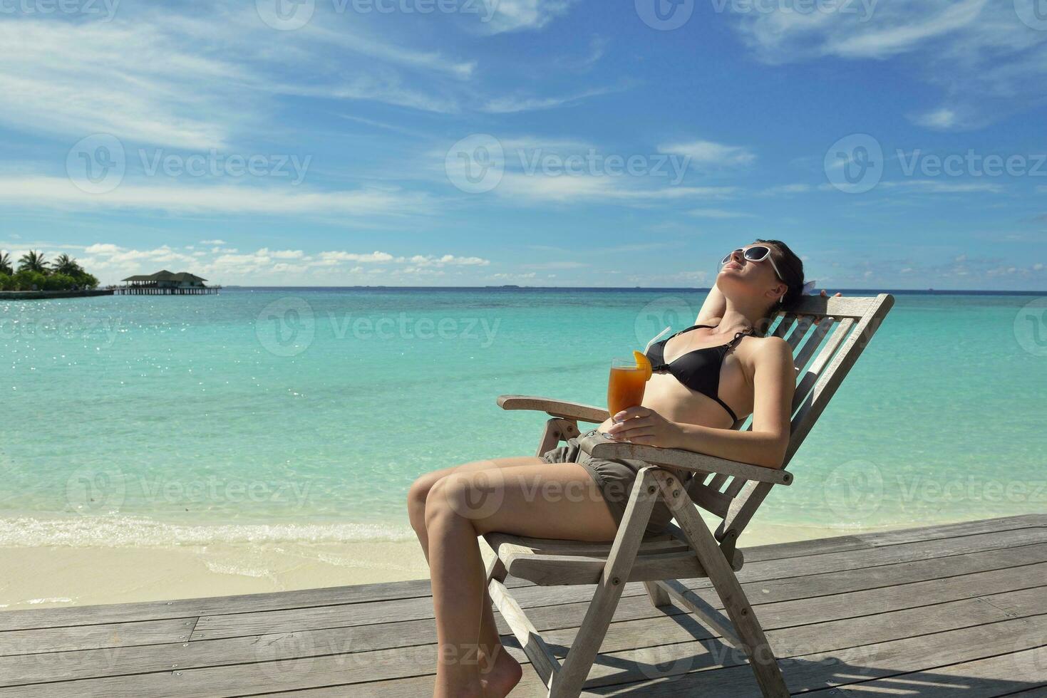 Beautiful young woman with a drink by the sea photo