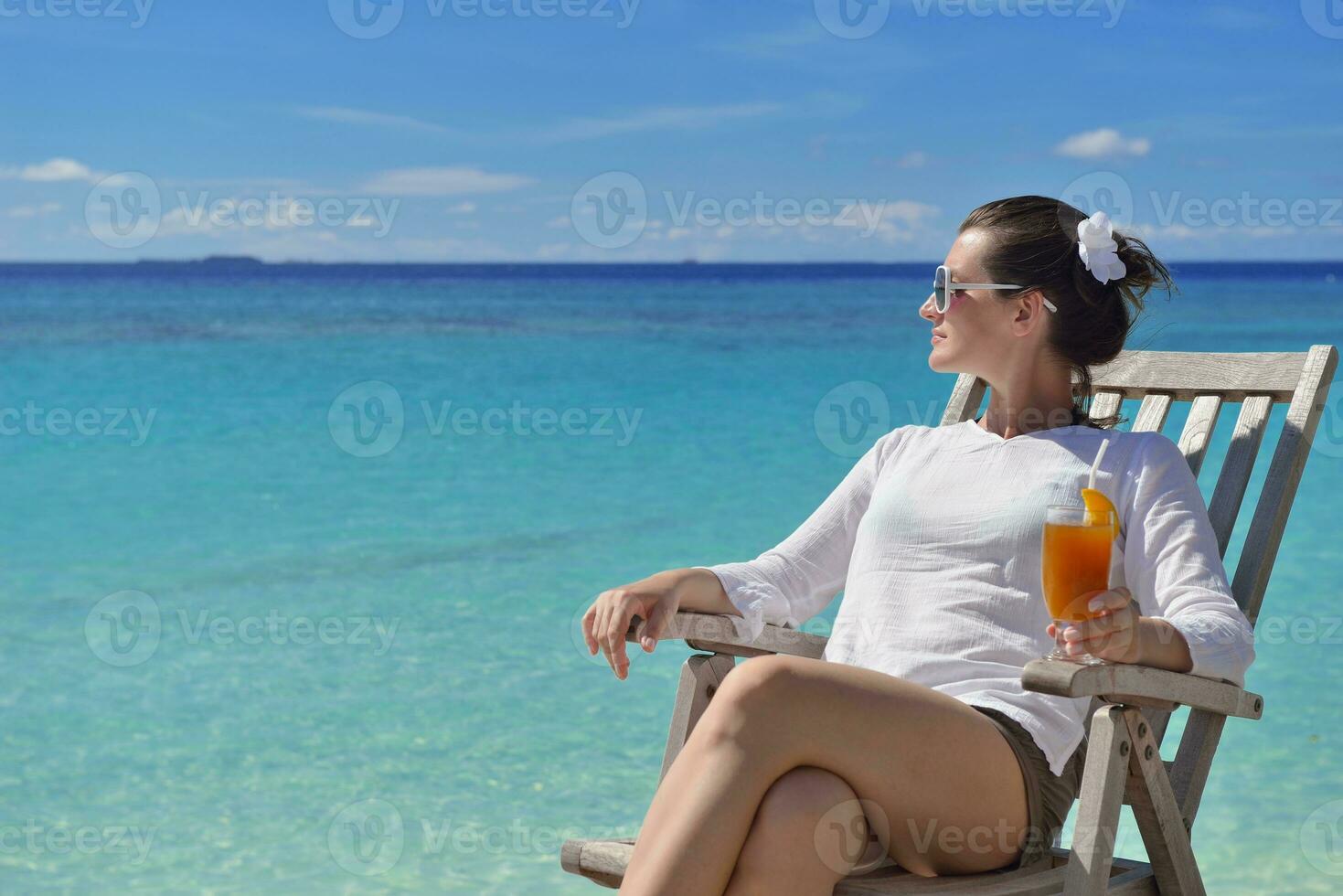 Beautiful young woman with a drink by the sea photo