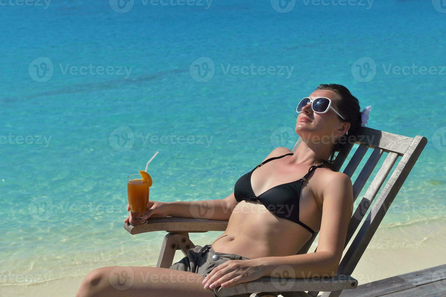 Beautiful young woman with a drink by the sea photo