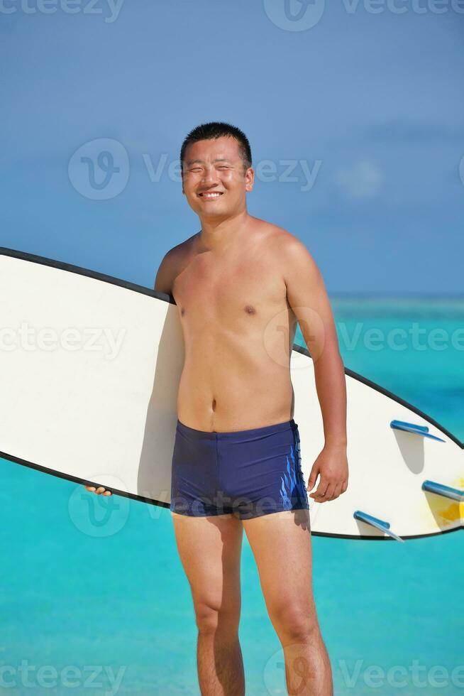 Man with surf board on beach photo