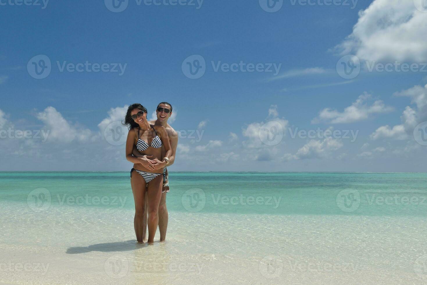 feliz pareja joven divertirse en la playa foto