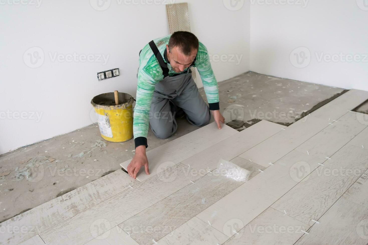 trabajador instalando las baldosas cerámicas con efecto madera en el suelo foto