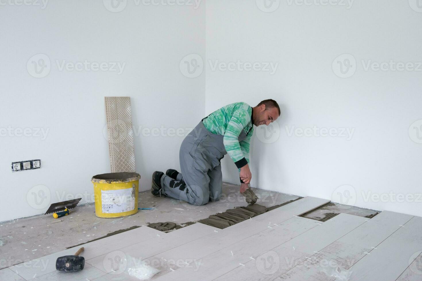 worker installing the ceramic wood effect tiles on the floor photo