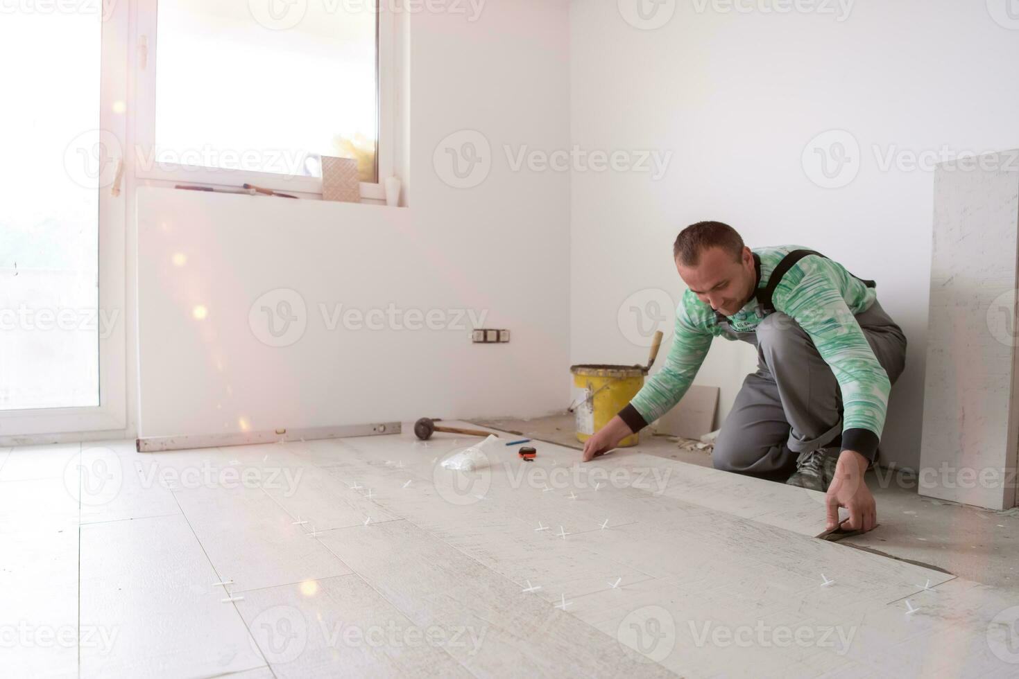 trabajador instalando las baldosas cerámicas con efecto madera en el suelo foto