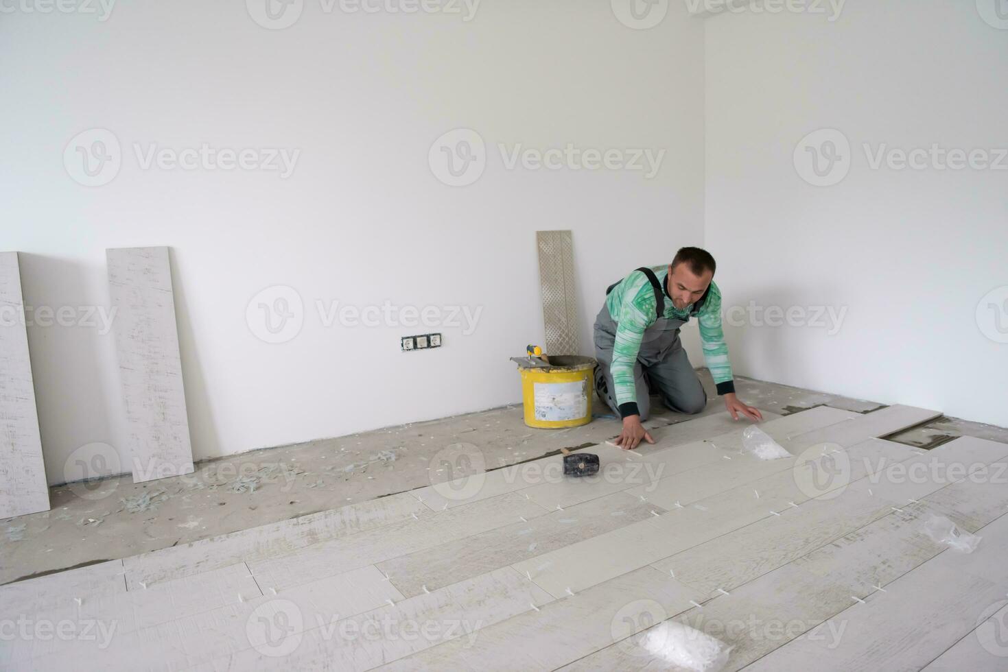 worker installing the ceramic wood effect tiles on the floor photo