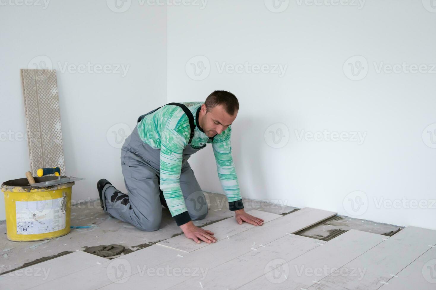 trabajador instalando las baldosas cerámicas con efecto madera en el suelo foto