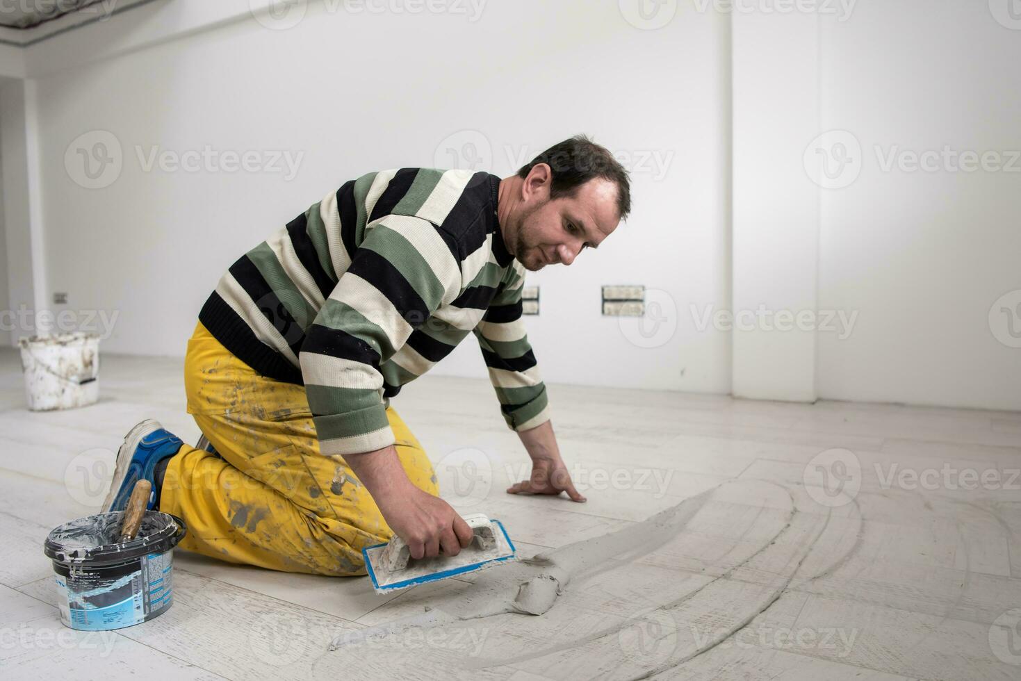 Tilers filling the space between ceramic wood effect tiles photo
