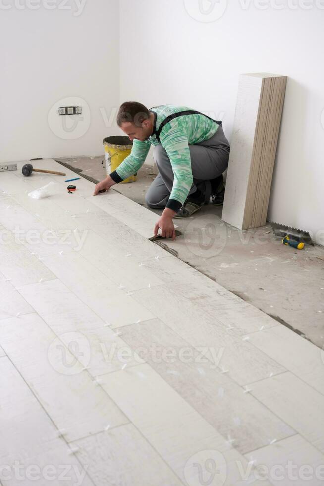 worker installing the ceramic wood effect tiles on the floor photo