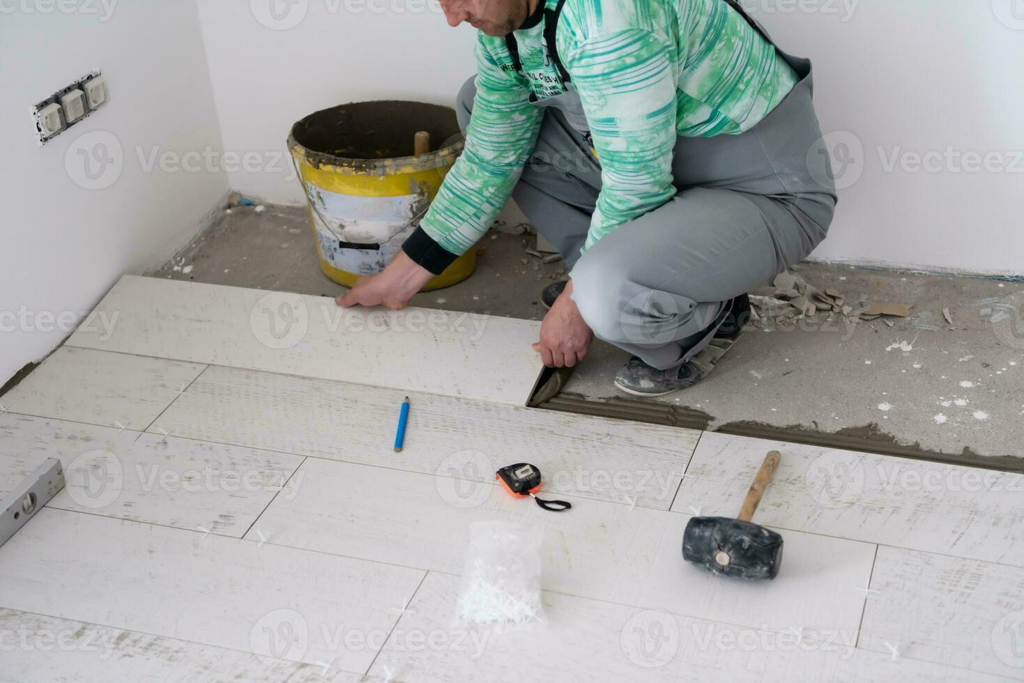 worker installing the ceramic wood effect tiles on the floor photo