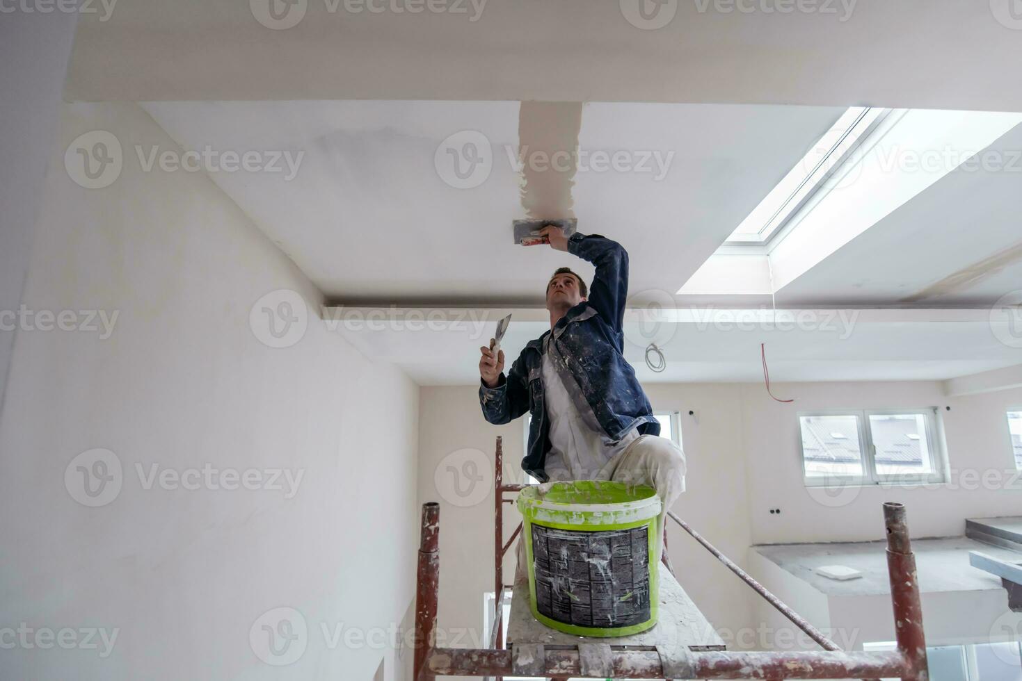 trabajador de la construcción enyesado en el techo de yeso foto