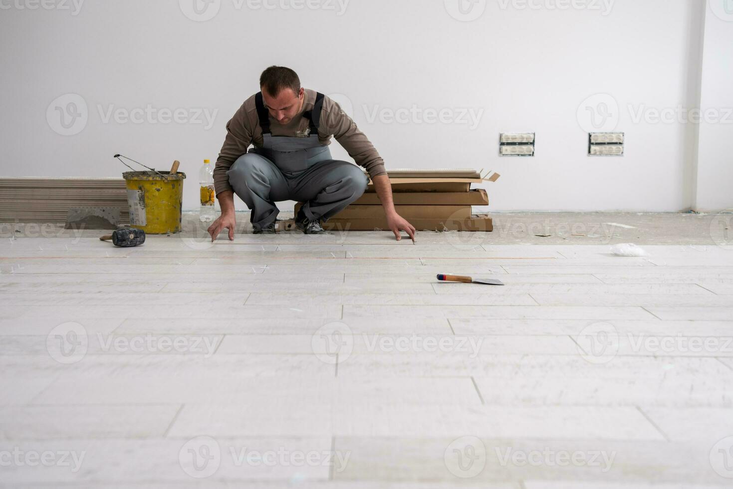 worker installing the ceramic wood effect tiles on the floor photo