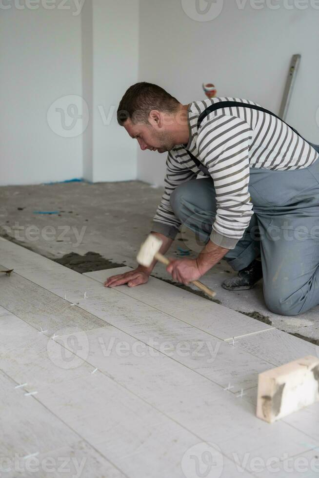 worker installing the ceramic wood effect tiles on the floor photo
