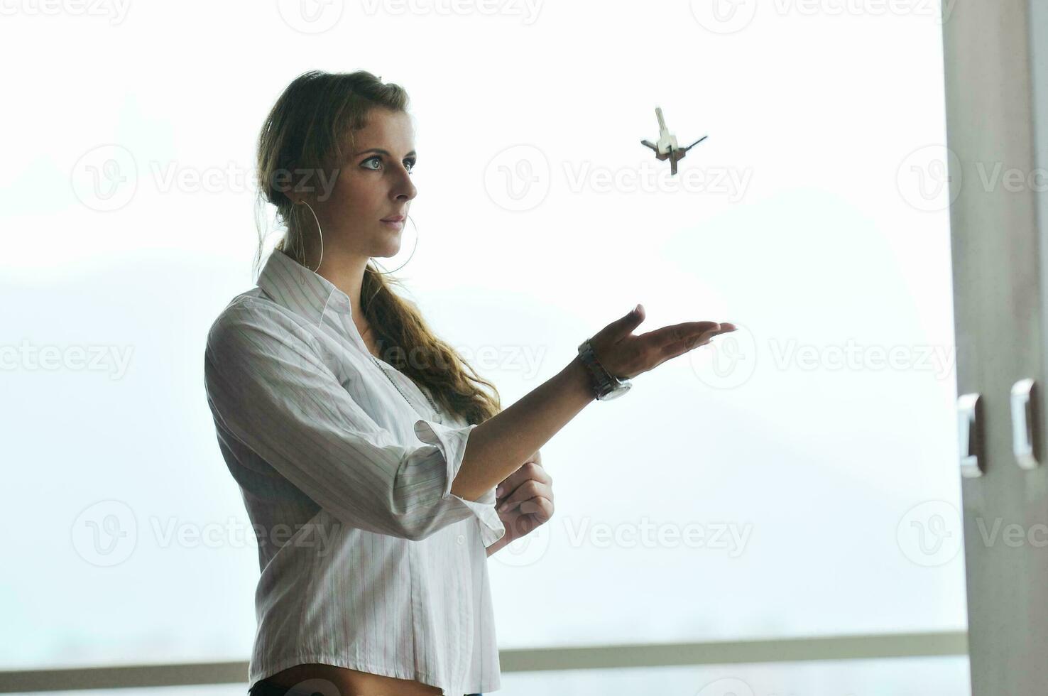 young woman throwing home keys in air photo