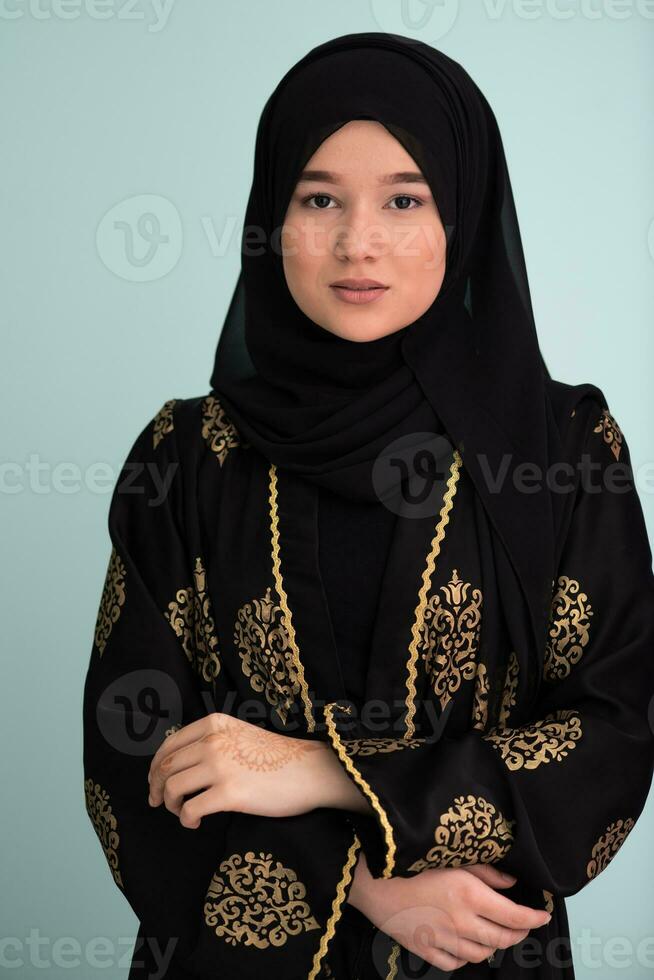 beautiful muslim woman in fashinable dress with hijab isolated on modern cyan background representing concept of modern islam and ramadan kareem photo