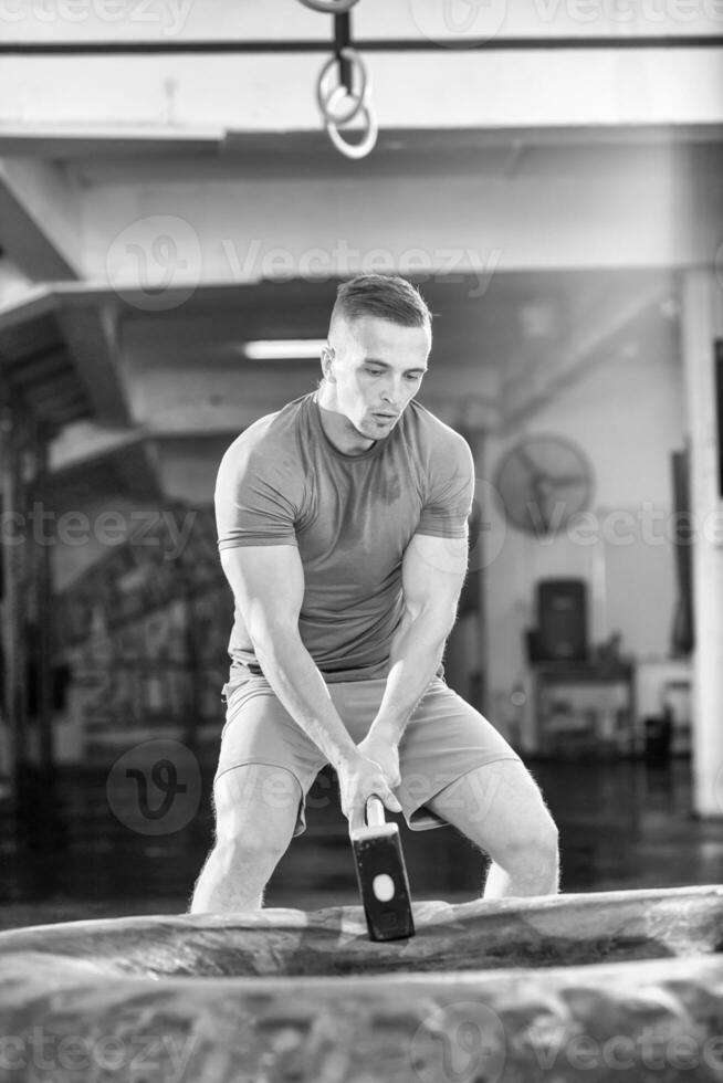 entrenamiento de hombre con martillo y neumático de tractor foto