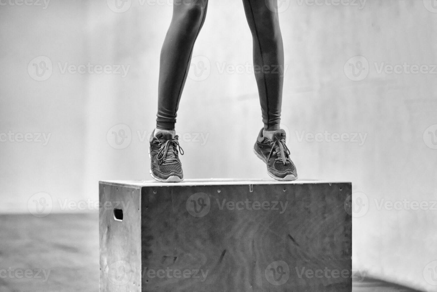 black woman is performing box jumps at gym photo