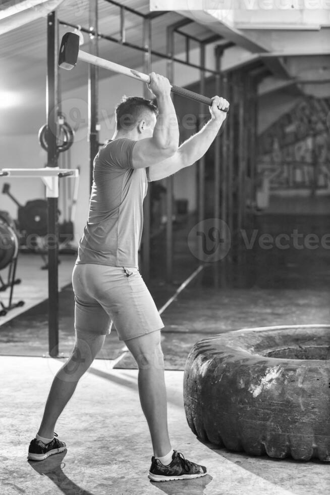 entrenamiento de hombre con martillo y neumático de tractor foto