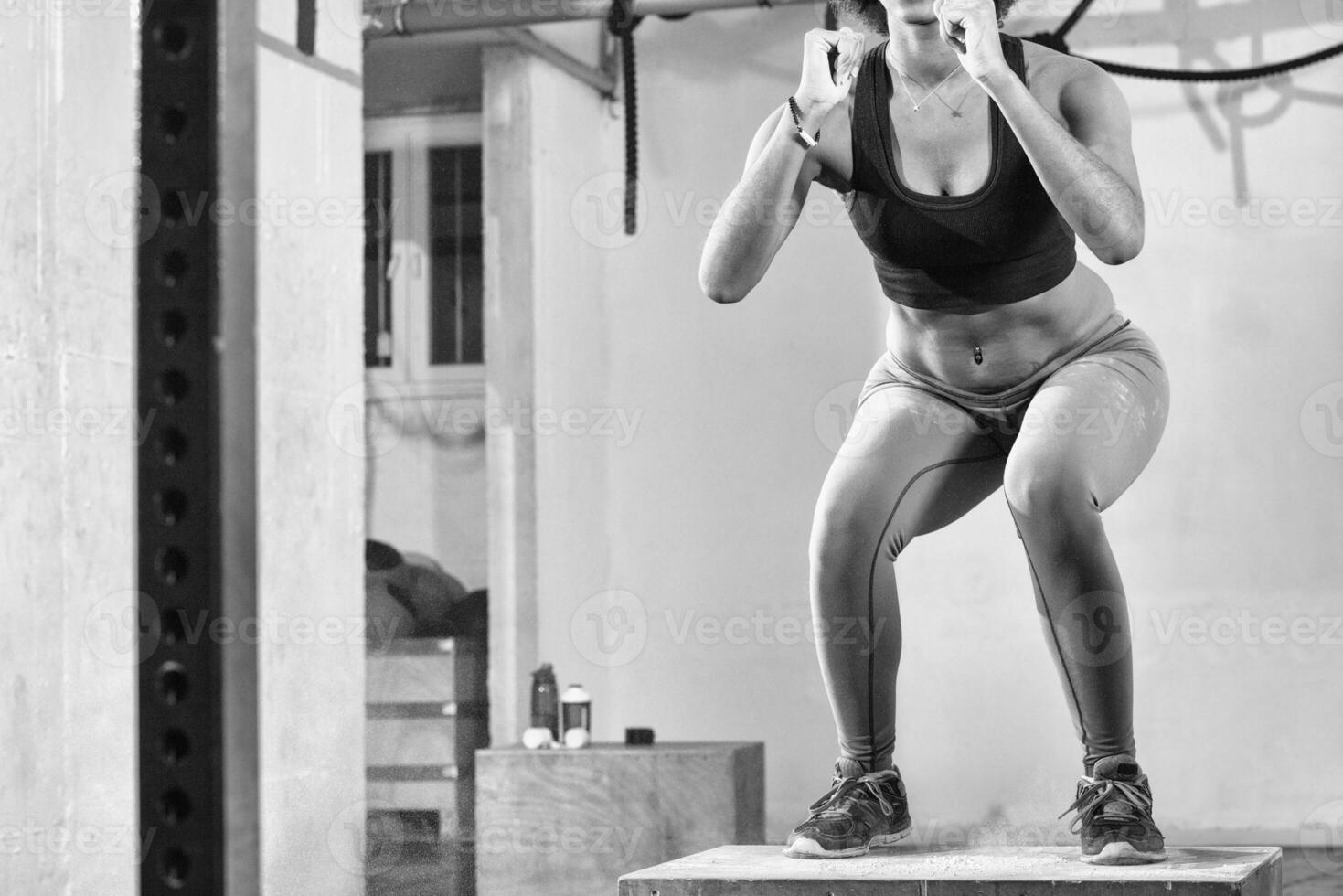 black woman is performing box jumps at gym photo