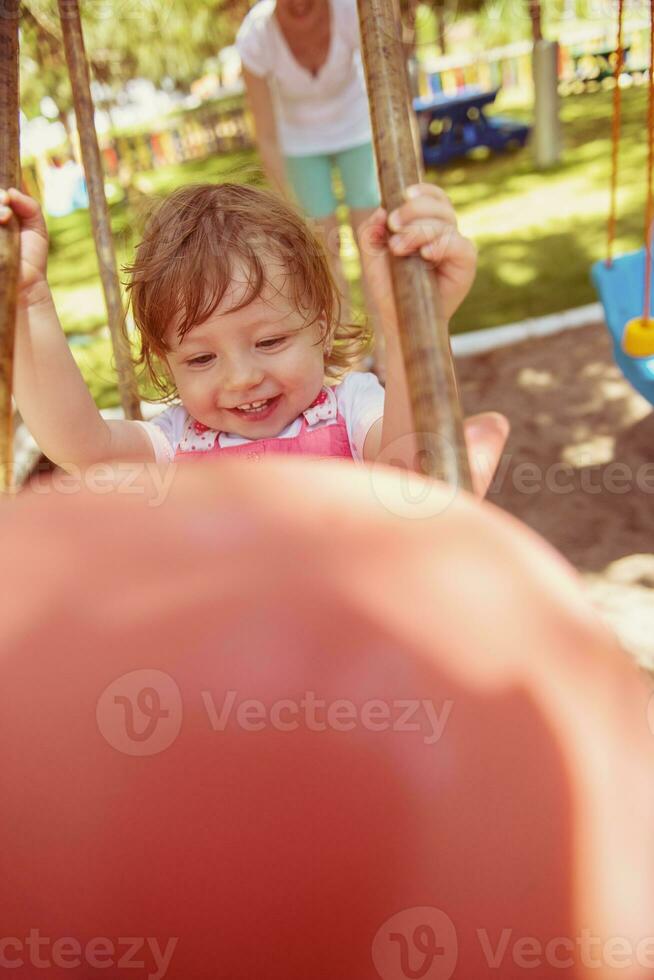 mother and daughter swinging in the park photo