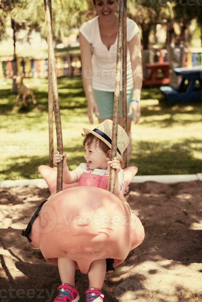 mother and daughter swinging in the park photo