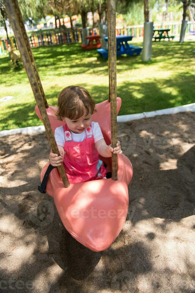 little girl swinging  on a playground photo