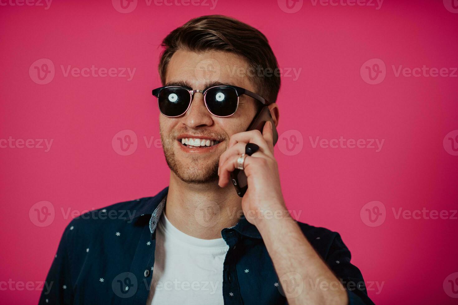 Portrait of a happy man using smartphone isolated over pink background. photo