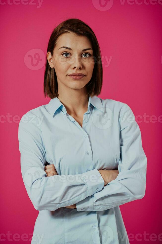 retrato Disparo de un hermosa rubio mujer de negocios en pie con brazos cruzado a aislado rosado antecedentes. foto