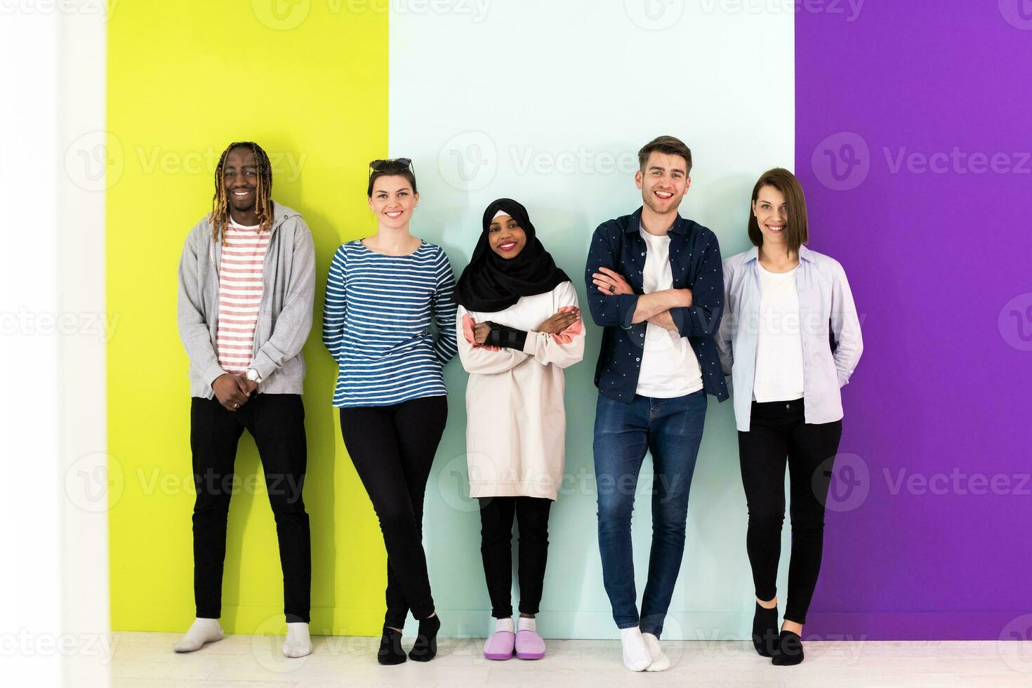 Diverse teenagers using mobile devices while posing for a studio photo in front of a colorful background