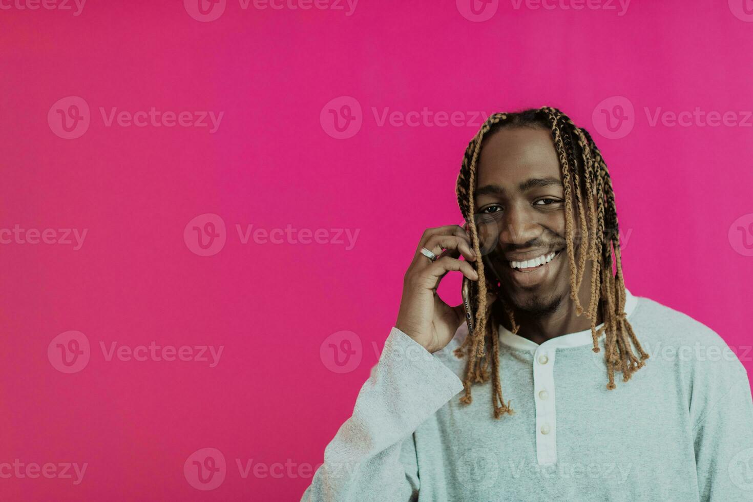 Modern young african student isolated on pink background using smartphone photo