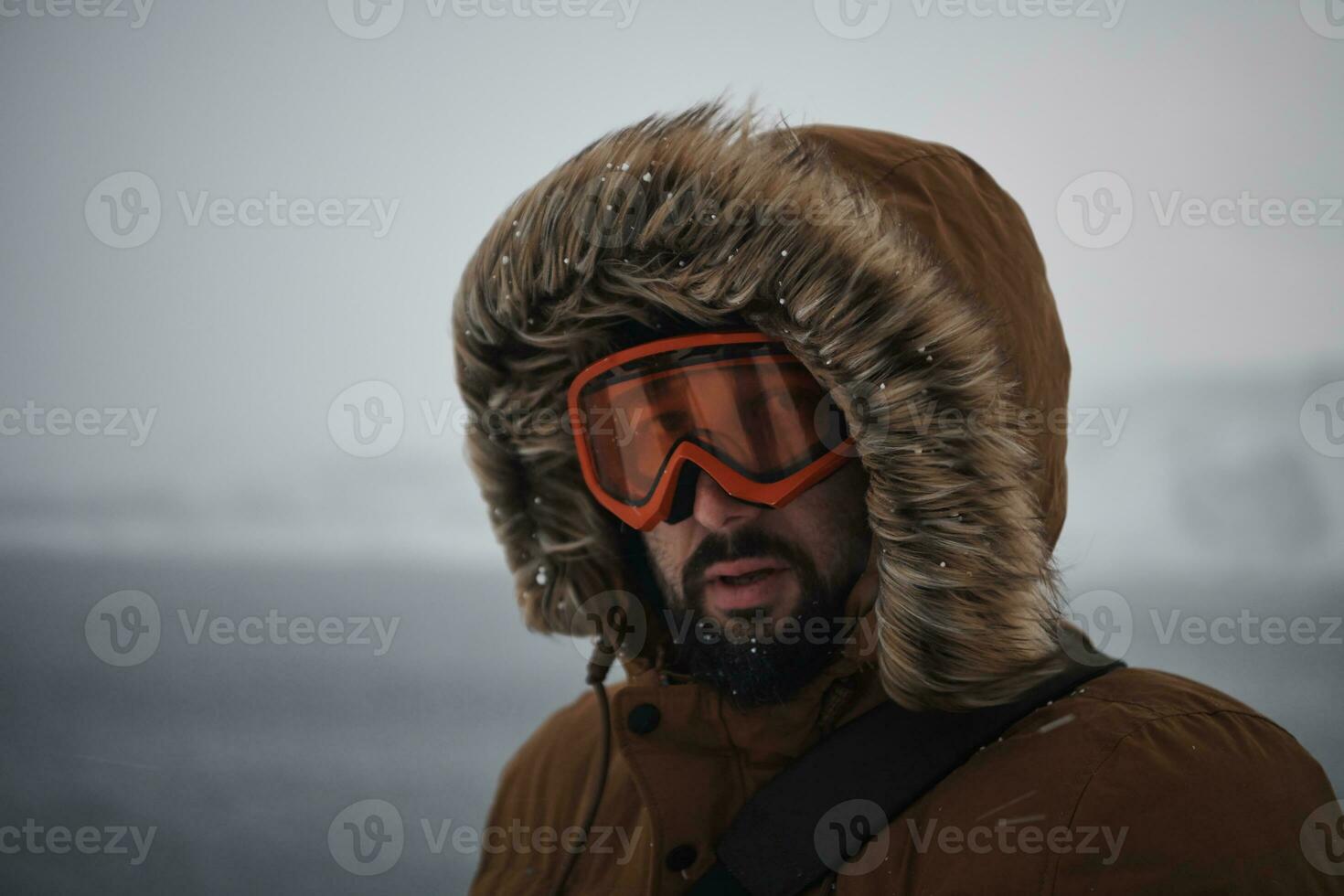 man at winter in stormy weather wearing warm  fur jacket photo