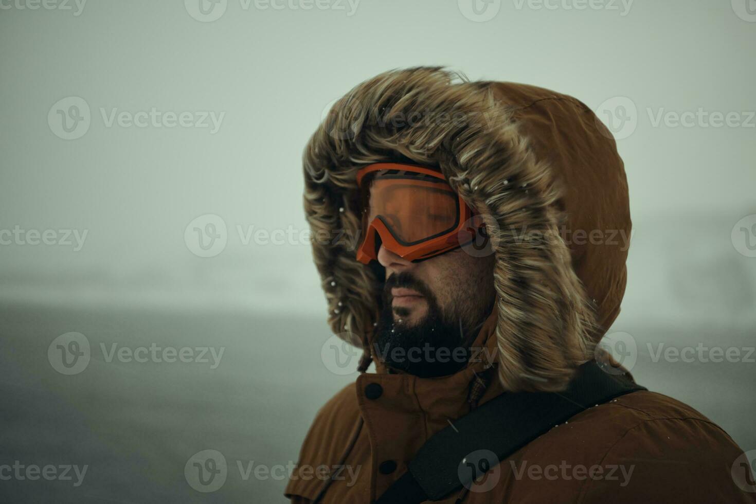 man at winter in stormy weather wearing warm  fur jacket photo