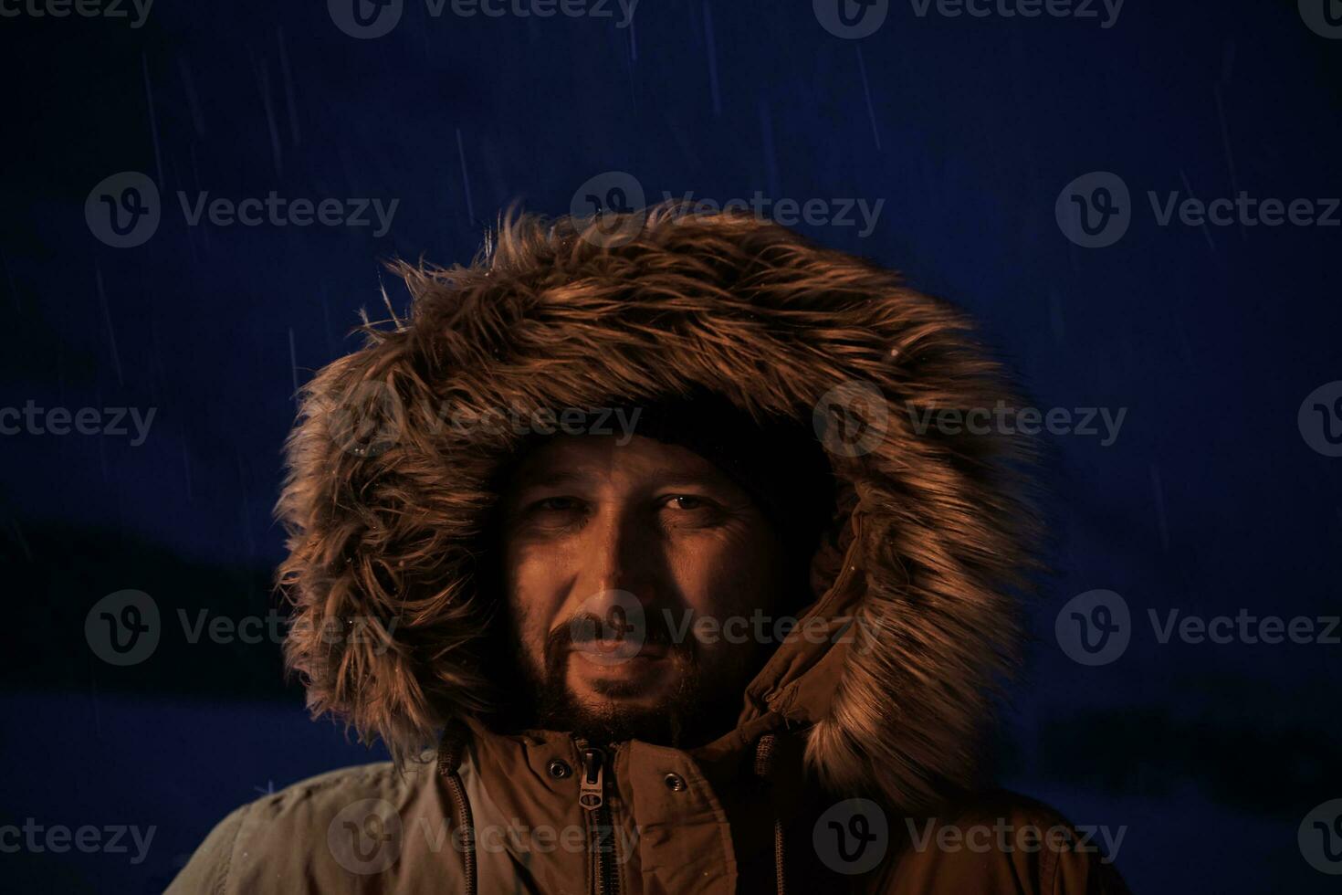 man at winter in stormy weather night  wearing warm  fur jacket photo