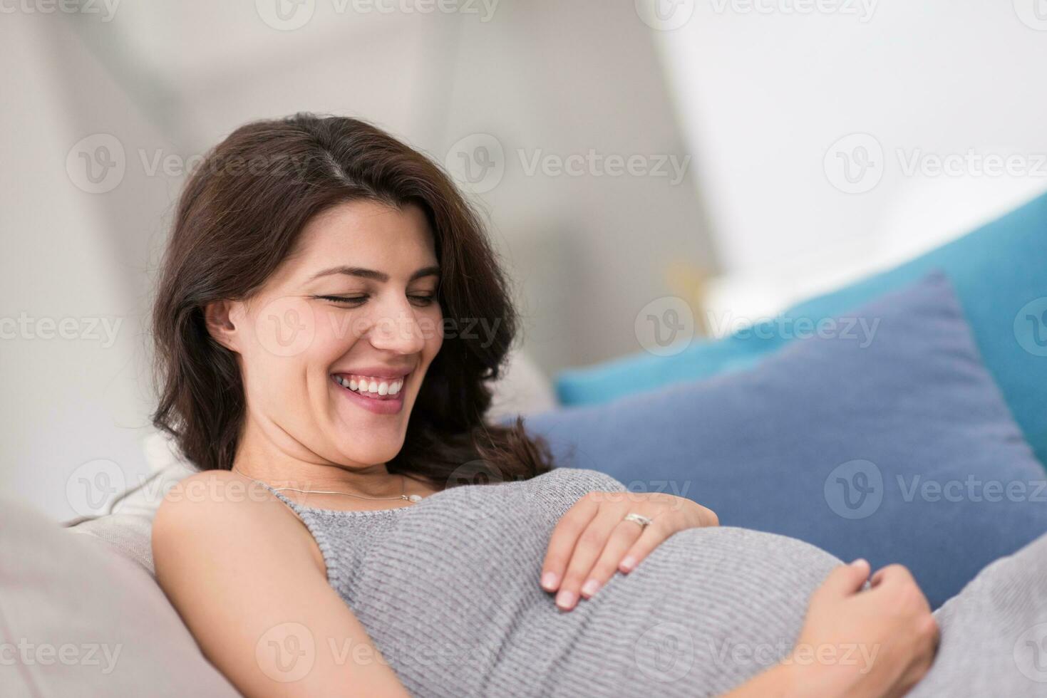 pregnant woman sitting on sofa at home photo