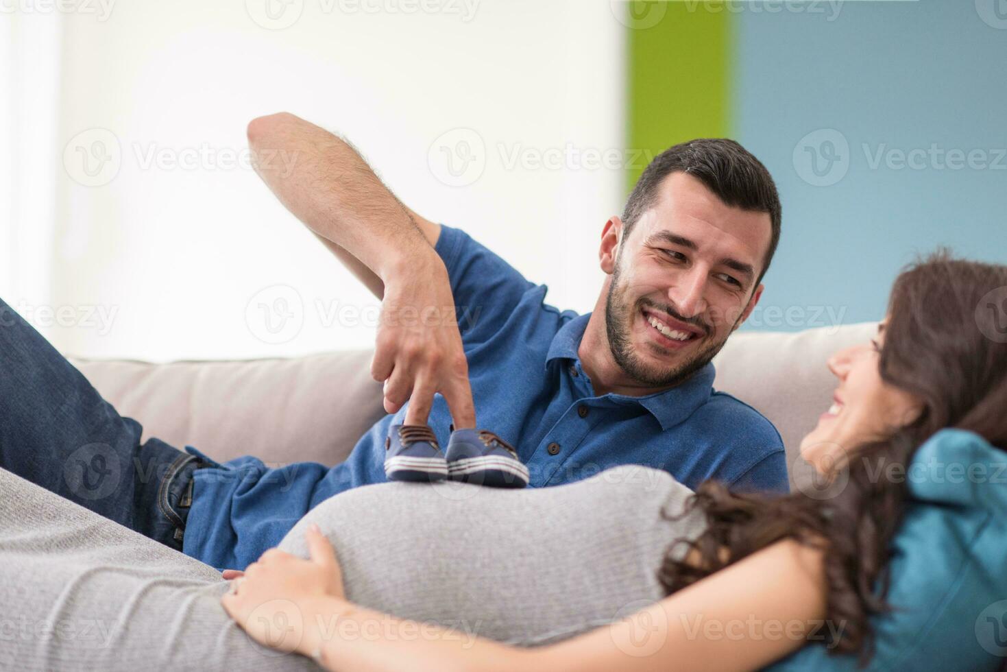 young pregnant couple relaxing on sofa photo
