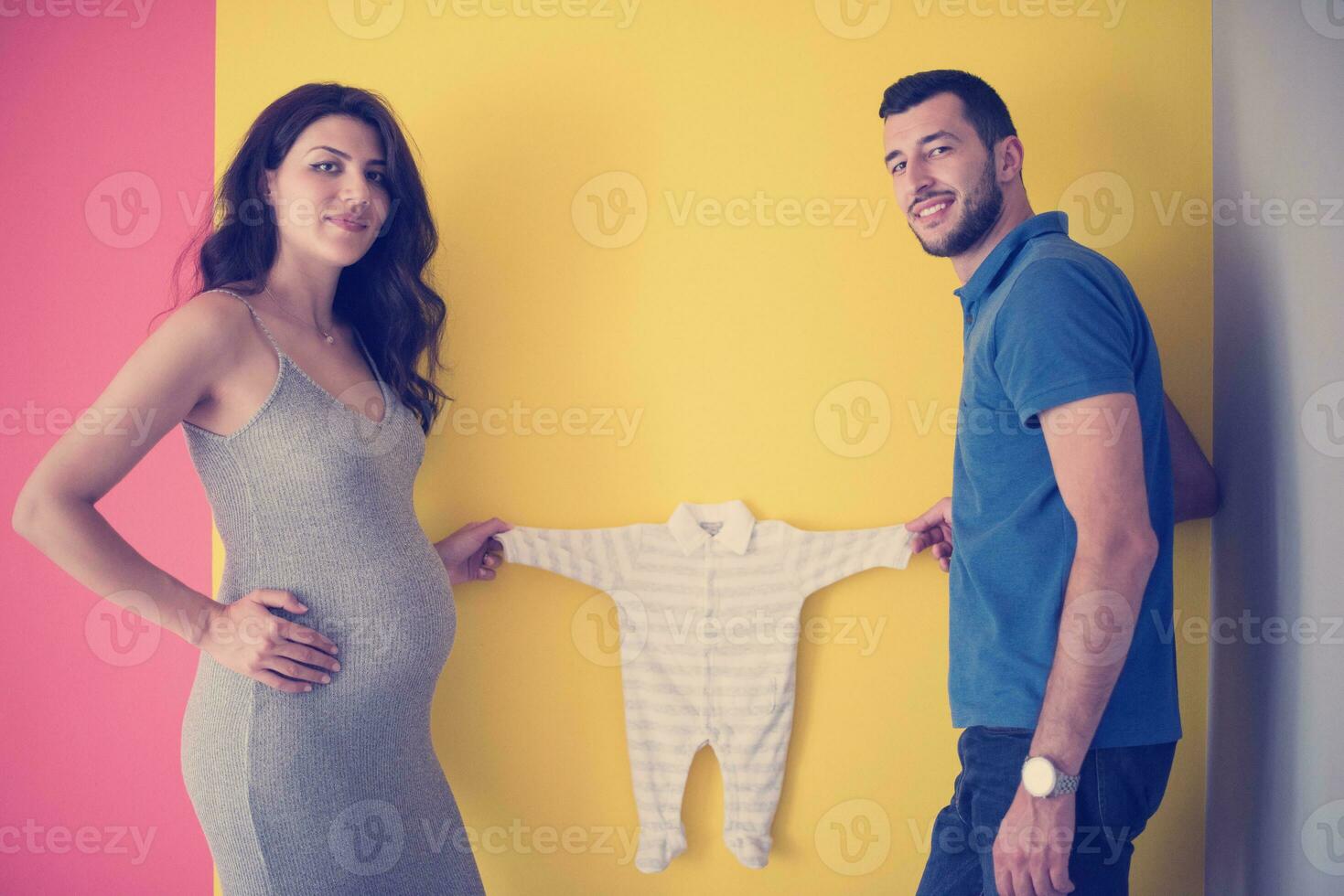 young couple holding baby bodysuits photo