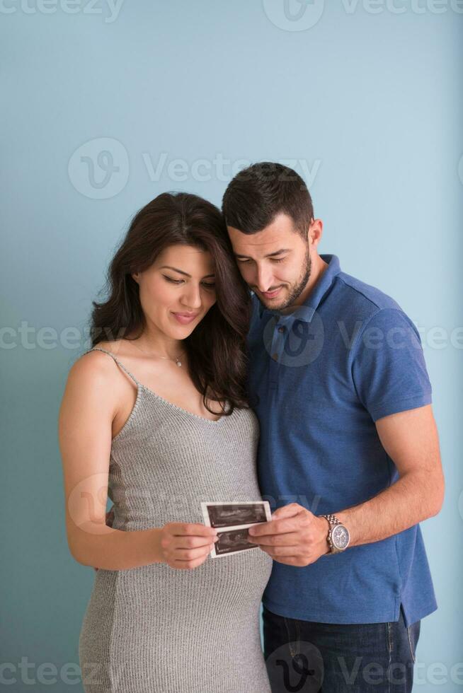 couple looking ultrasound picture isolated on blue background photo