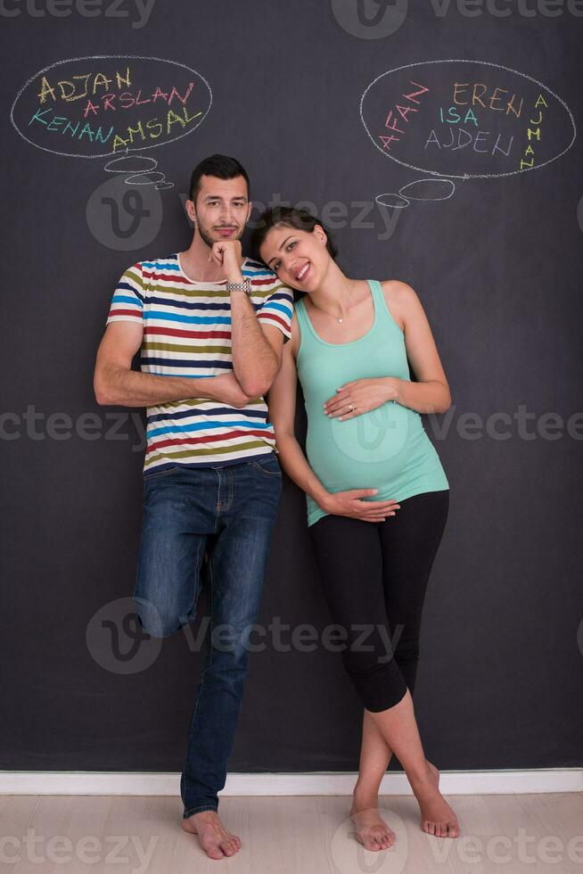 pregnant couple writing on a black chalkboard photo