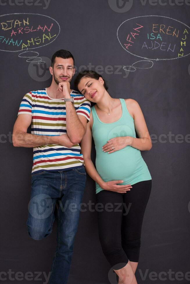 pregnant couple writing on a black chalkboard photo