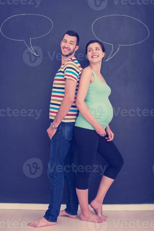 pregnant couple writing on a black chalkboard photo