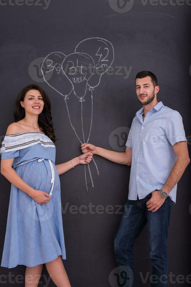 pregnant couple drawing their imaginations on chalk board photo