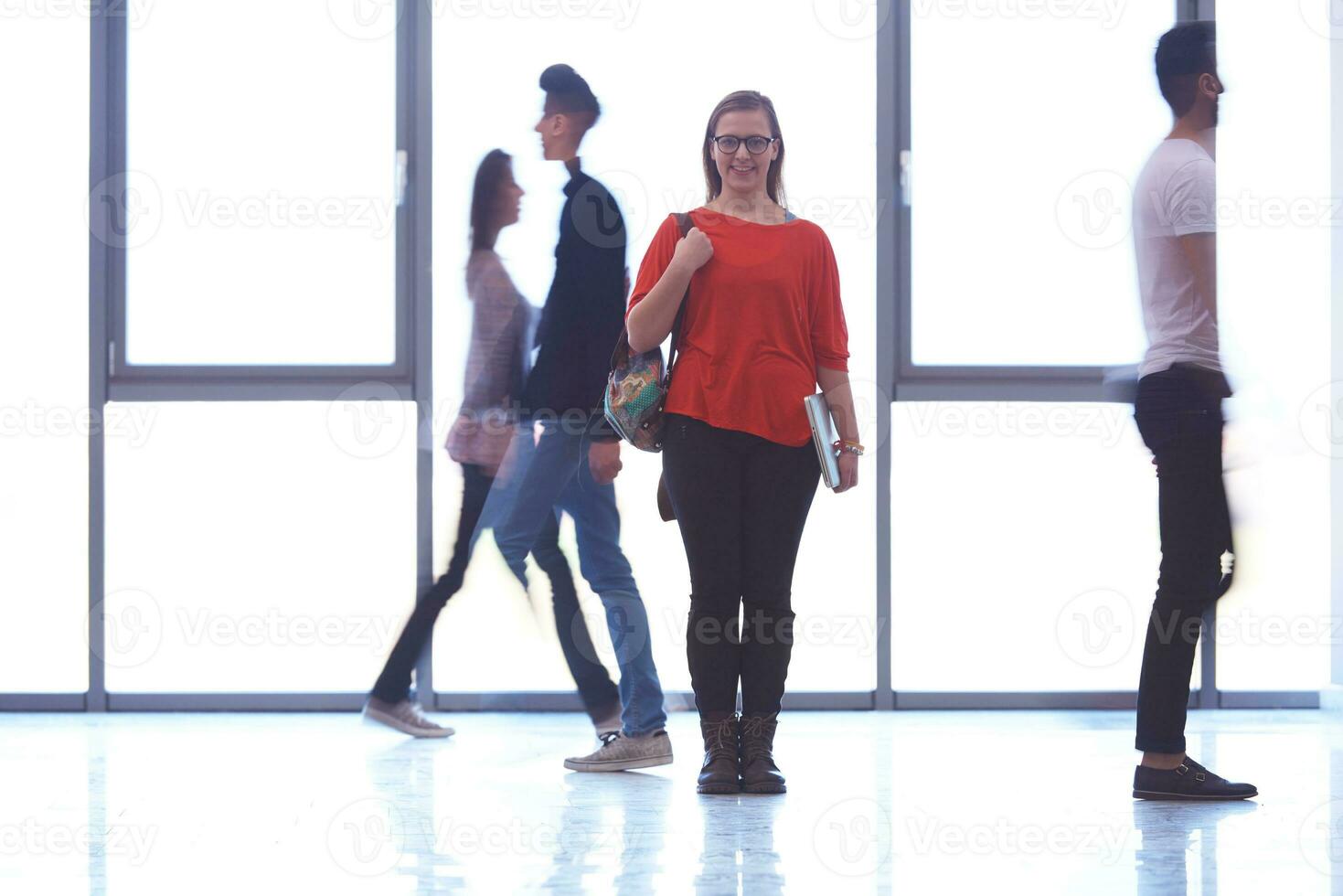 estudiante de pie con una laptop, grupo de personas pasando foto