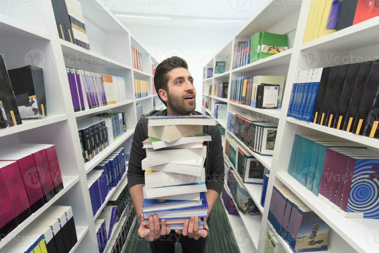 Student holding lot of books in school library photo