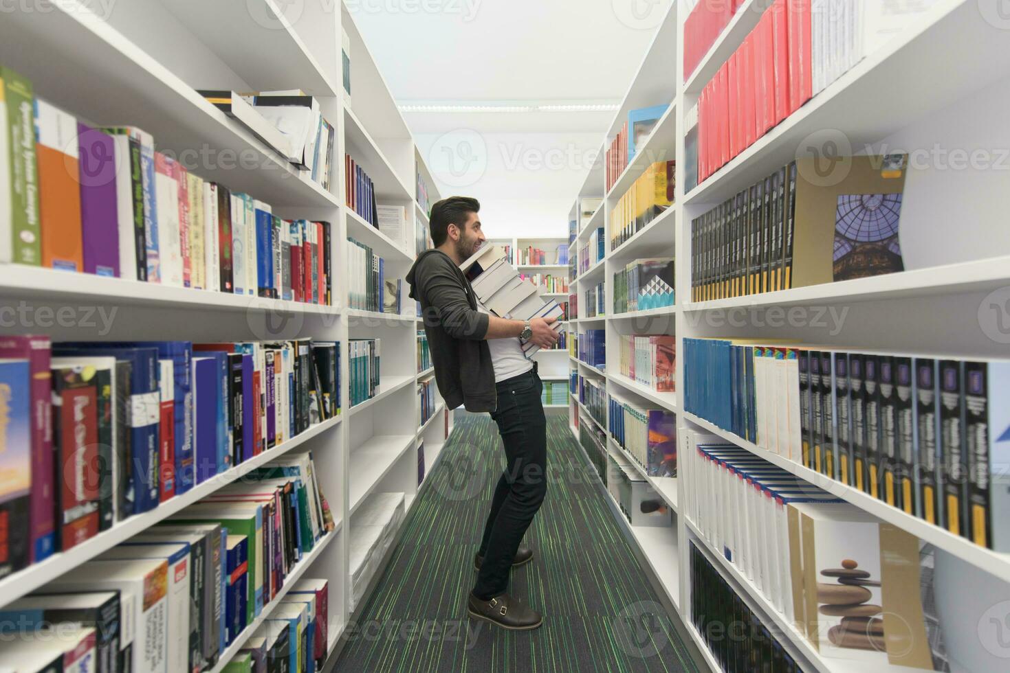 Student holding lot of books in school library photo