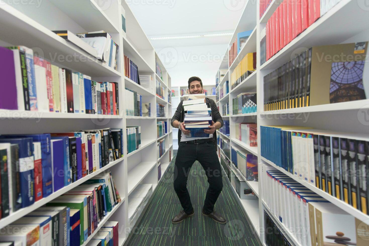 Student holding lot of books in school library photo