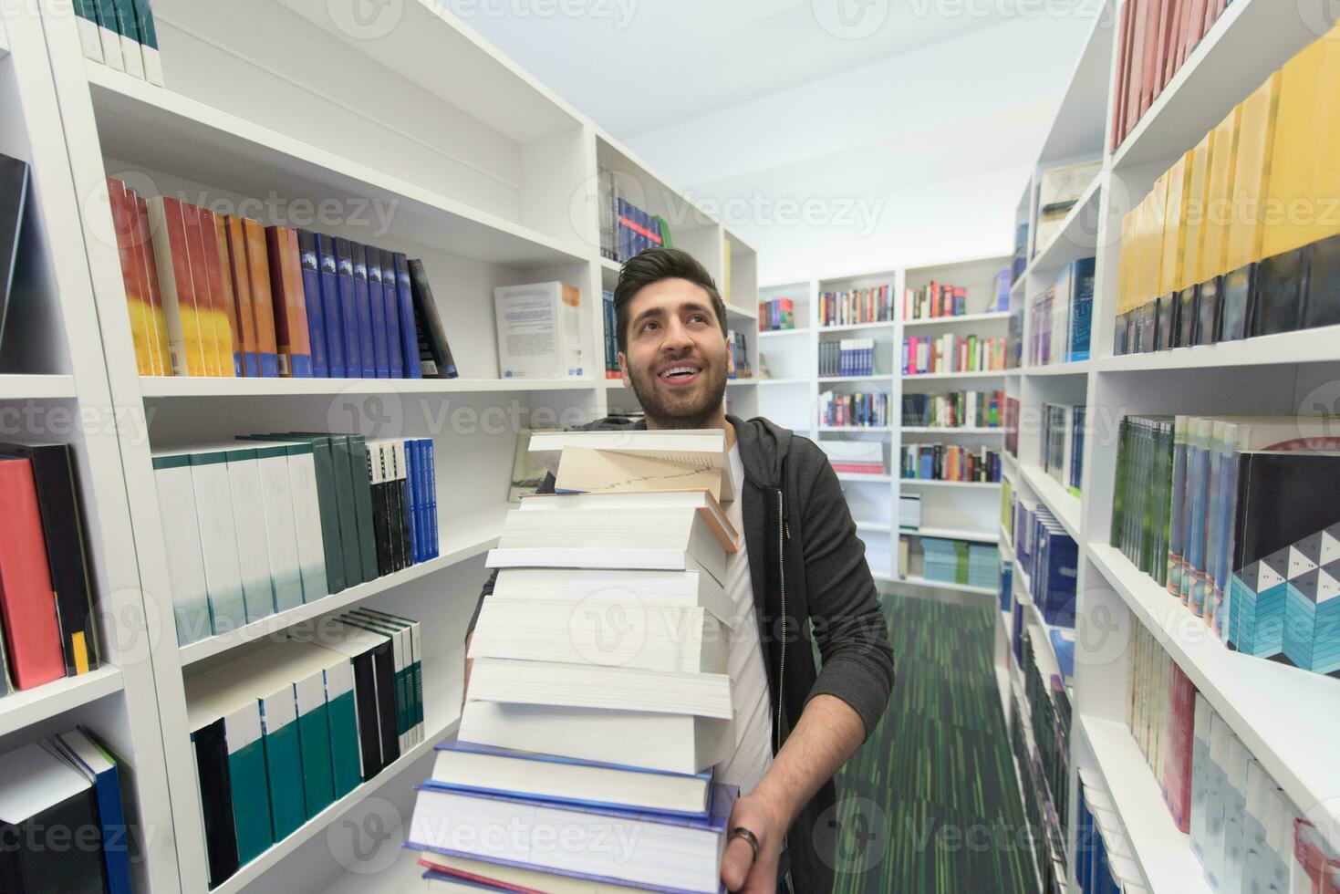 Student holding lot of books in school library photo