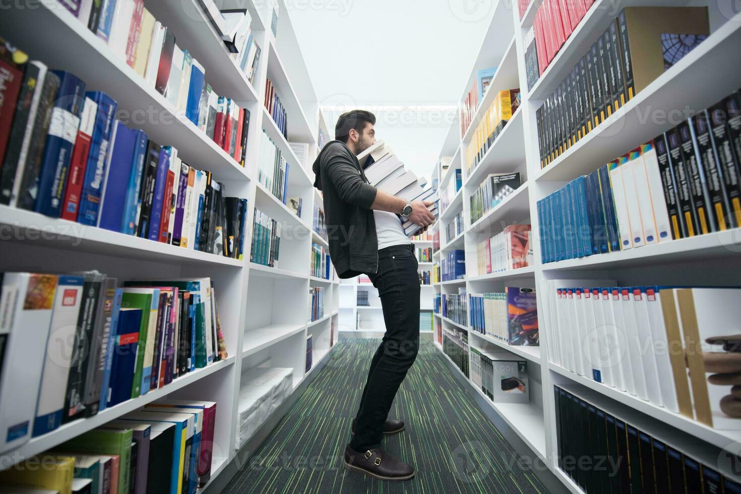 Student holding lot of books in school library photo