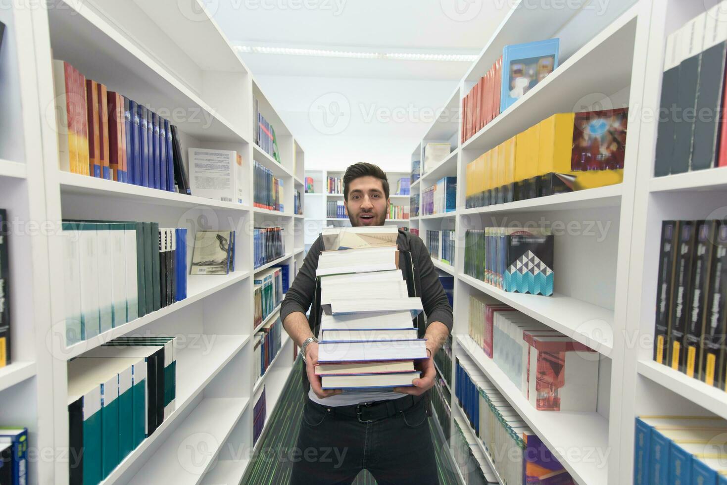Student holding lot of books in school library photo