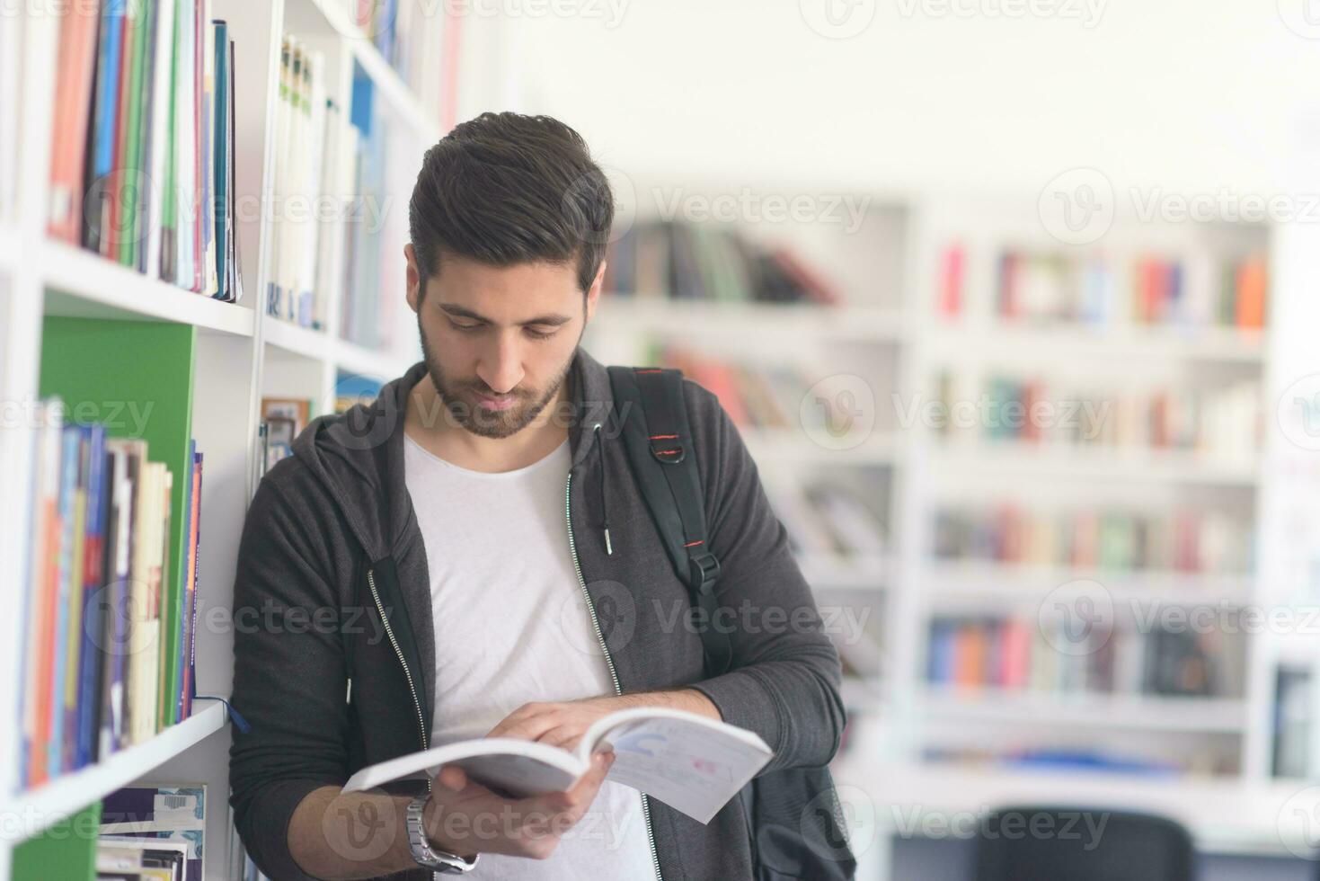 portrait of student while reading book  in school library photo